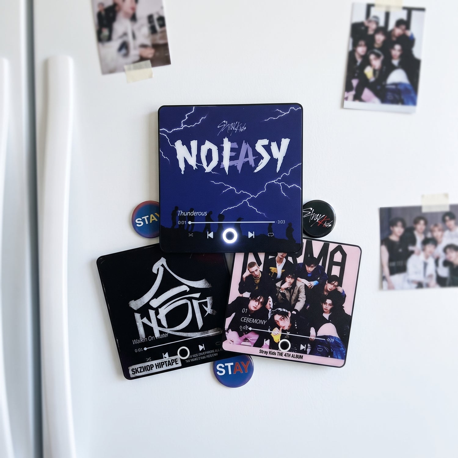 Three StayTunes magnets arranged on a white fridge with Stray Kids photocards and STAY badges